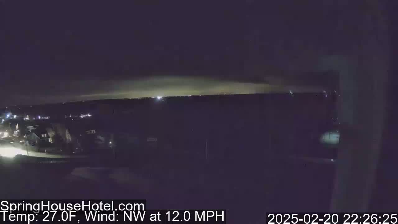 A nighttime view of a suburban area with a hazy or cloudy sky, a northwest wind of 12 mph, and a temperature of 27 degrees Fahrenheit.