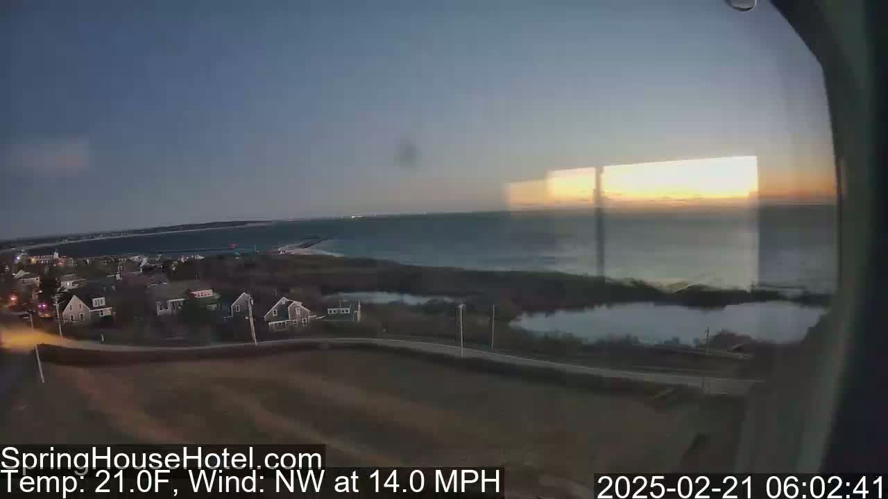 A coastal town at sunset, with a 21°F temperature and a 14 mph northwest wind.