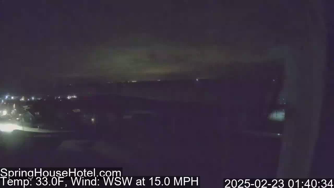 A nighttime, long-range view of a city landscape under a partly cloudy sky with a 15 mph wind from the west-southwest, and a temperature of 33°F.