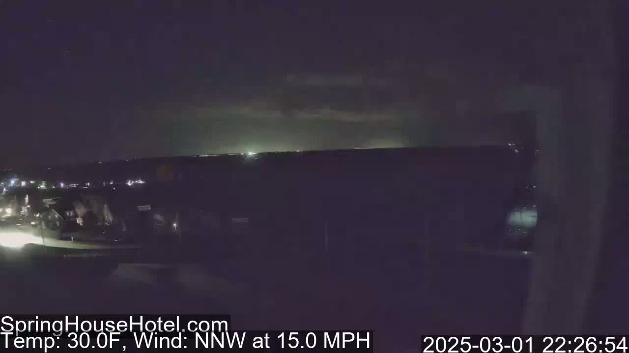 A nighttime view of a suburban area with a 30°F temperature and a 15 mph northwest wind shows a distant horizon lit by faint lights.
