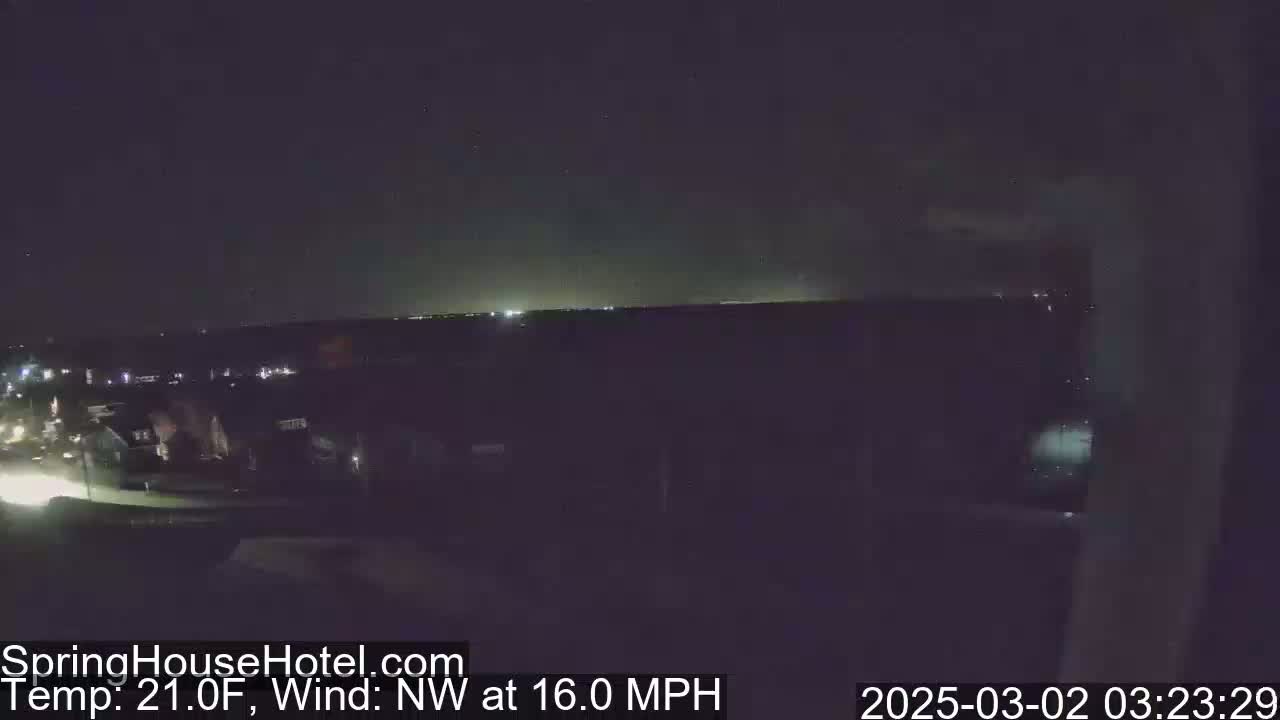 A nighttime view of a suburban area with a NW wind at 16.0 mph and a temperature of 21.0°F.