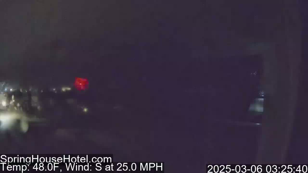 A blurry nighttime view of a dark, outdoor scene with a 25 mph south wind and a temperature of 48°F.