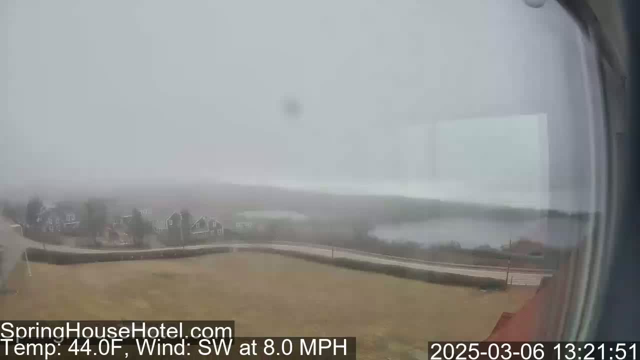 A foggy, overcast view shows a road curving past a body of water and houses, with a southwest wind blowing at eight miles per hour and a temperature of 44 degrees Fahrenheit.