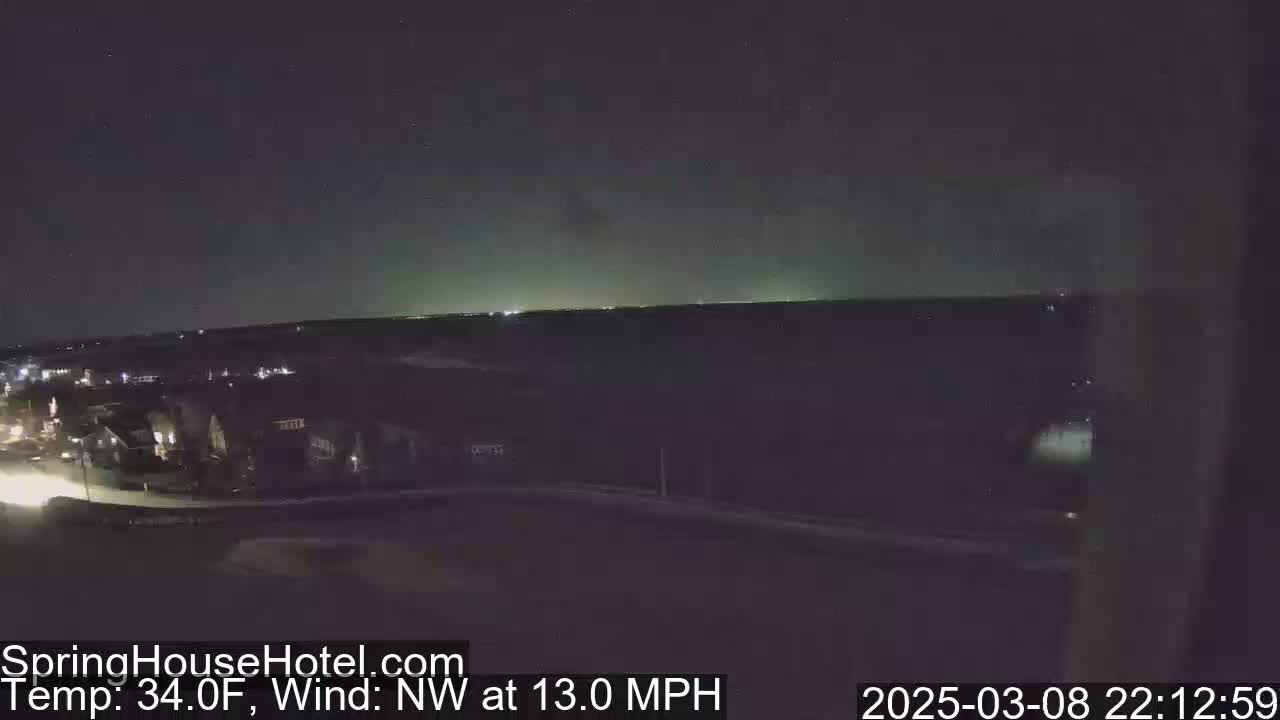 A nighttime view of a residential area under a dark sky with a northwest wind at 13 mph and a temperature of 34 degrees Fahrenheit.