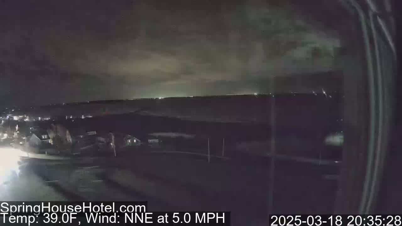A nighttime, elevated view of a suburban area under a partly cloudy sky with a 5 mph wind from the north-northeast, and a temperature of 39°F.