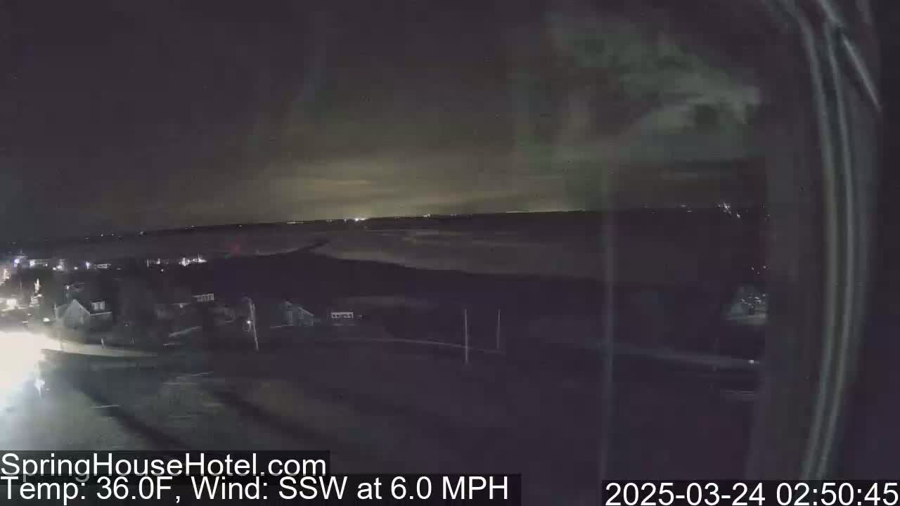 A nighttime view of a suburban area near a body of water under a dark sky with a 36°F temperature and a 6.0 mph southwest wind.