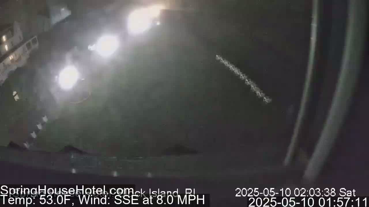 A nighttime outdoor scene shows bright lights illuminating a dark area, with a faint, light streak across the sky under an otherwise clear night and a moderate southeast wind.