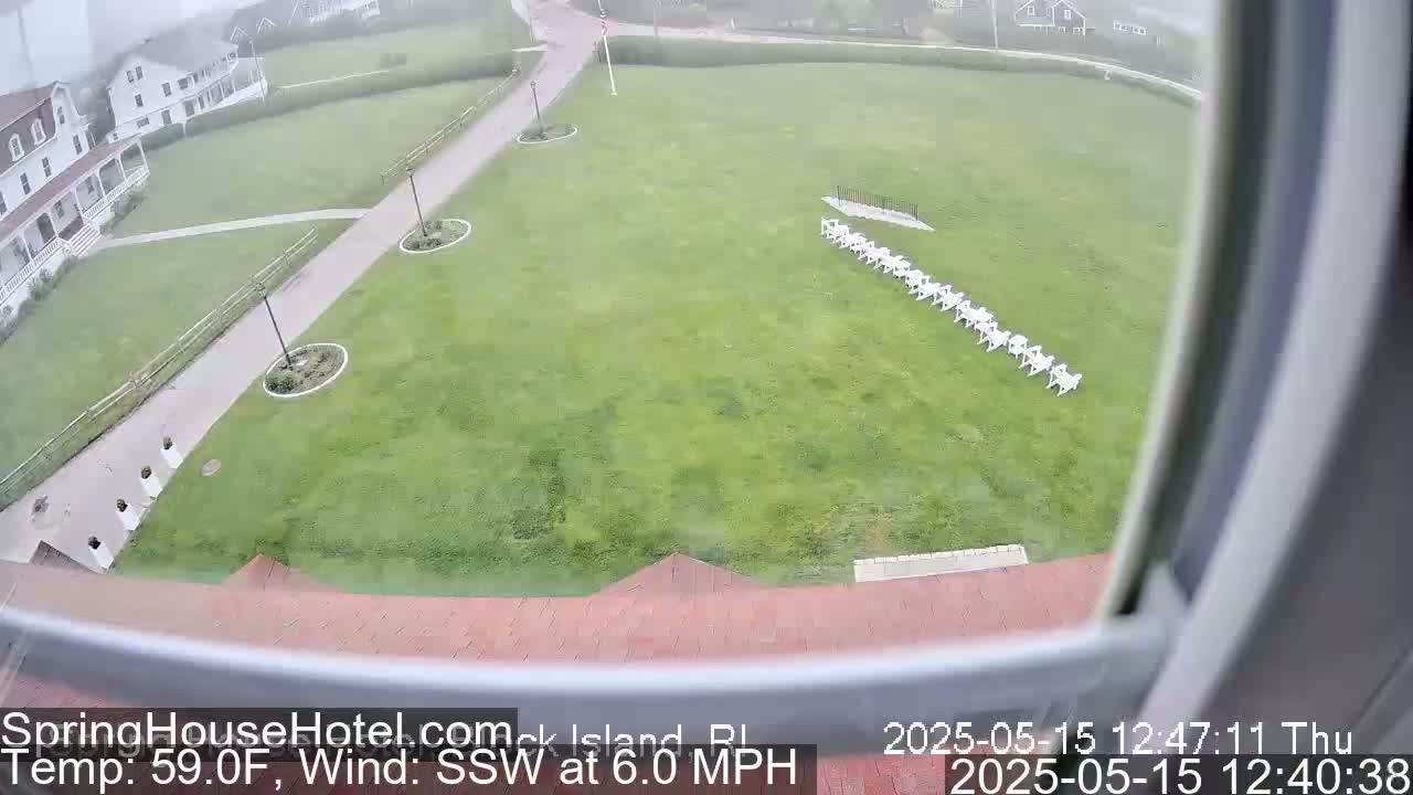 A grassy lawn with a row of white chairs is seen from an elevated viewpoint on an overcast day with a south-southwesterly wind of 6 mph and a temperature of 59°F.