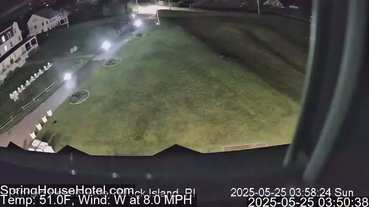 A nighttime, overhead view of a grassy area with a building and some outdoor furniture, under a clear sky with a west wind at 8 mph and a temperature of 51 degrees Fahrenheit.