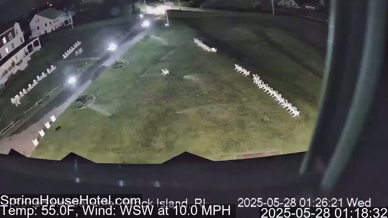 A nighttime, overhead view shows a grassy area with rows of white chairs, a building with lights, and a wind of 10 mph from the west-southwest.