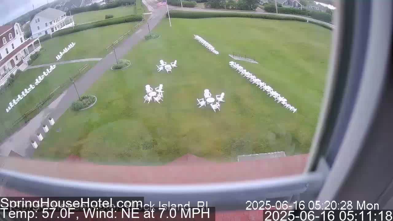 A grassy area with numerous white chairs arranged in rows and small groupings, viewed from an elevated position on a partly cloudy day with a northeast wind at 7 mph and a temperature of 57°F.