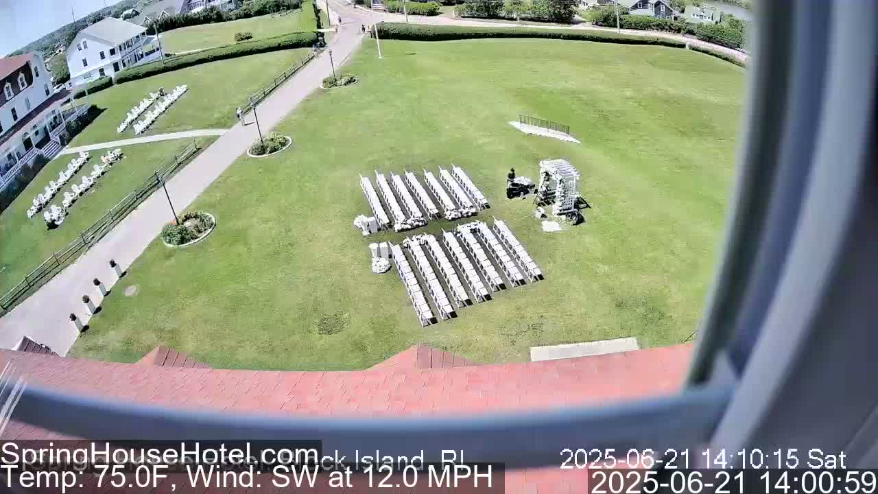 An outdoor scene shows a grassy area with rows of white chairs set up for an event, a person near a decorative archway, and a building in the background on a sunny day with a southwest wind at 12 mph and a temperature of 75 degrees Fahrenheit.