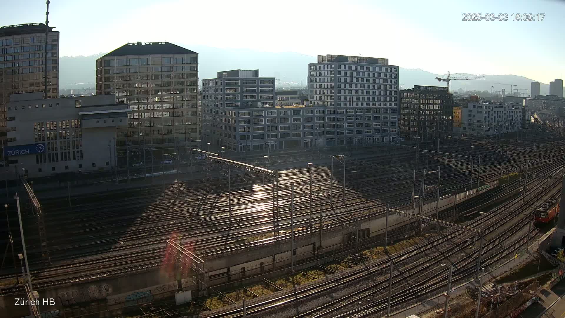 A sunny day view of a large railway yard surrounded by modern buildings.