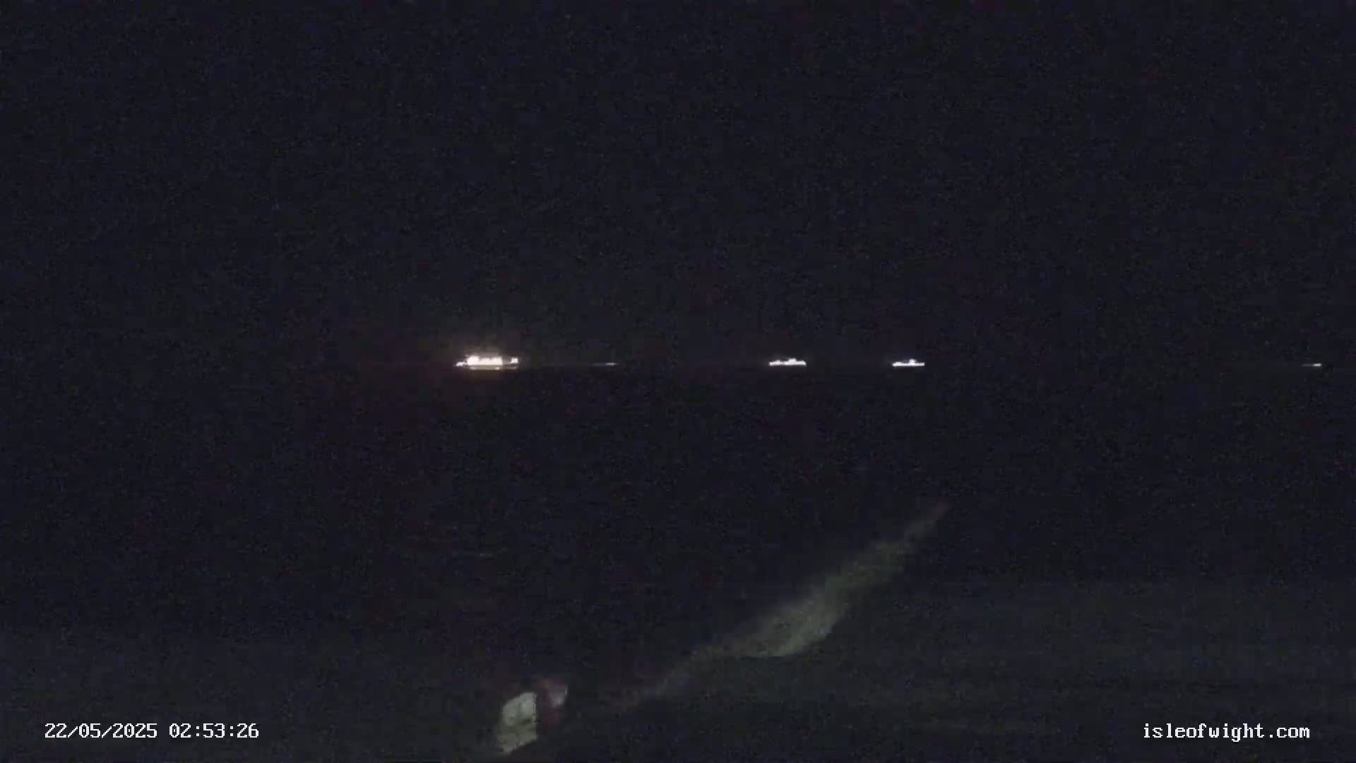 Several ships are visible on a dark, nighttime body of water.