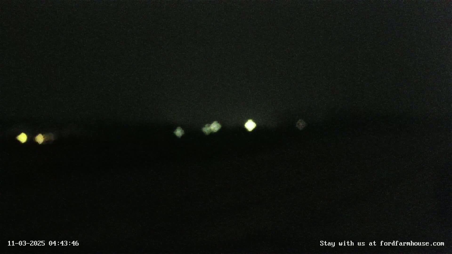 A dark, nighttime scene shows several distant, blurred lights on the horizon.