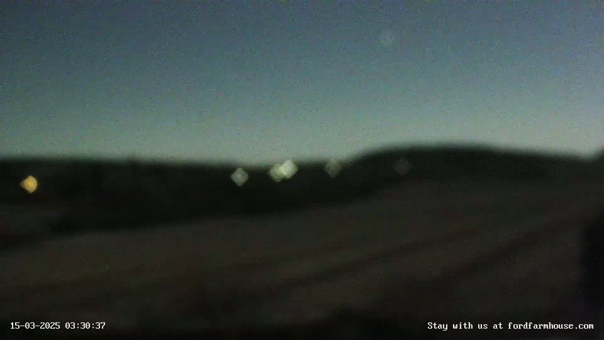 A blurry, dark image shows a distant, dark hill silhouetted against a twilight sky.