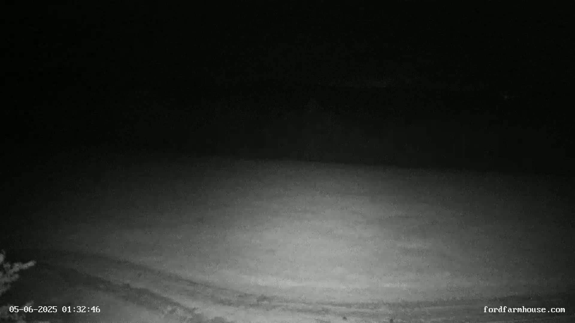 A nighttime, low-light view of a flat, dark ground possibly a field, under a dark sky.