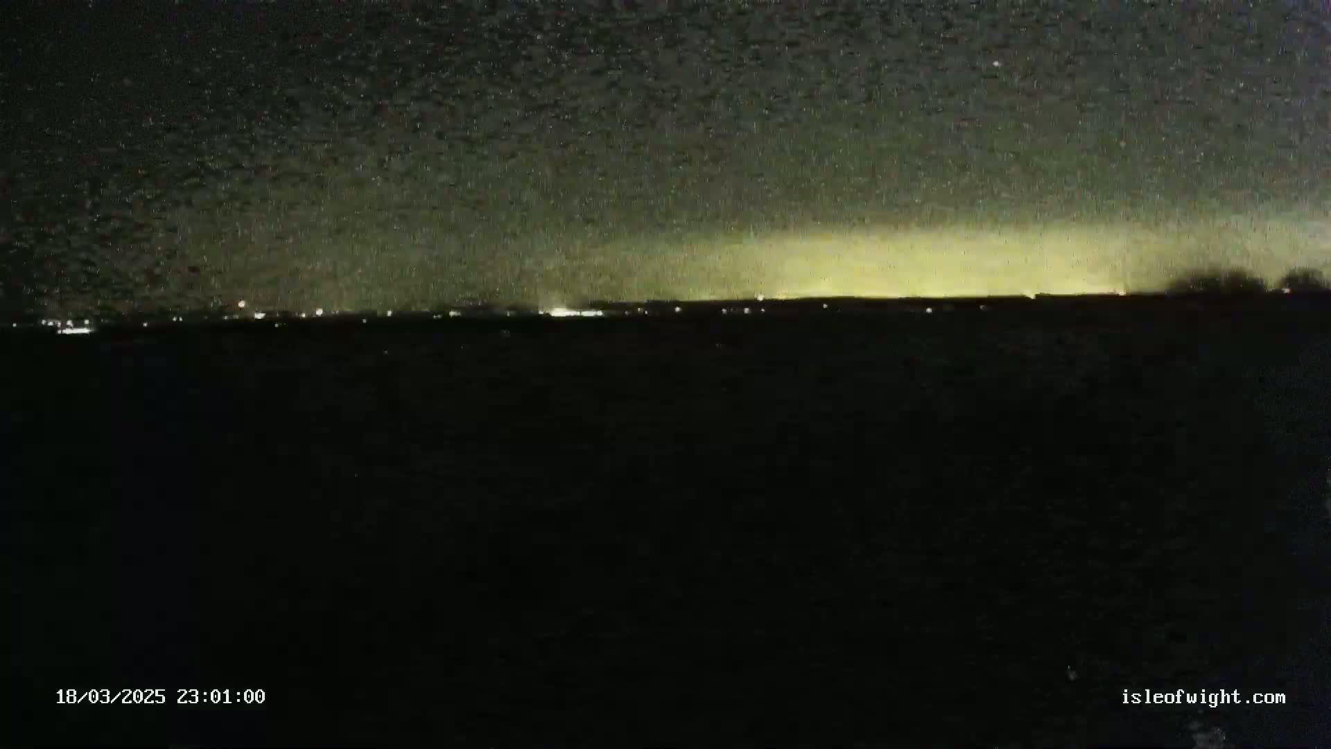 A nighttime view shows a faintly illuminated horizon under a starry sky.
