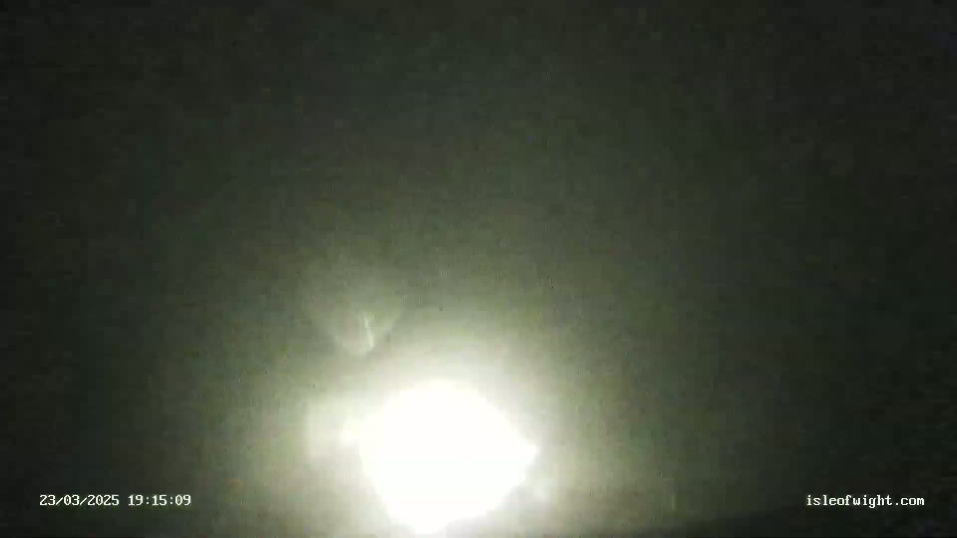 A bright light, possibly a spotlight or headlight, is visible in the dark, hazy night.