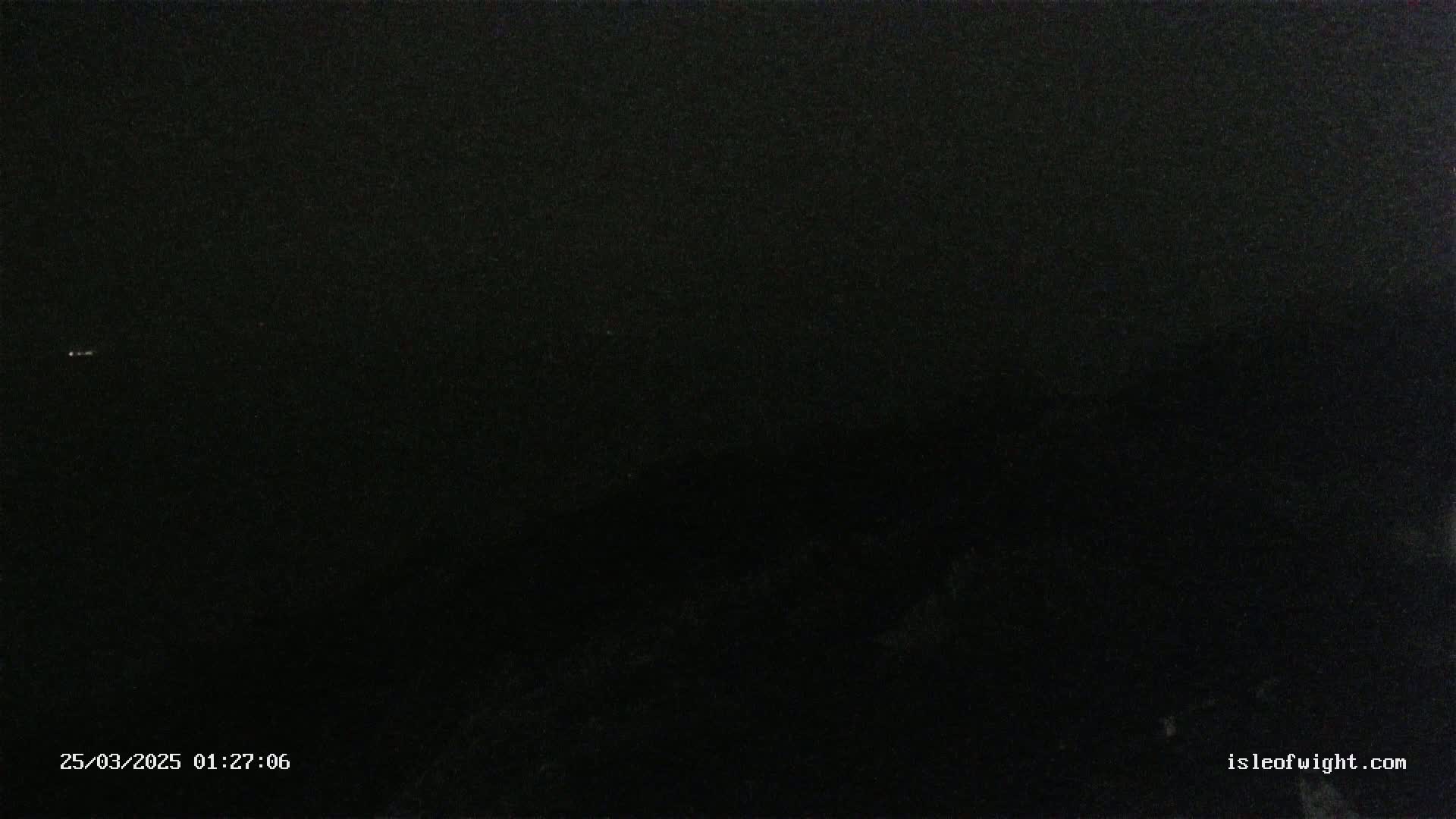 A very dark nighttime scene with a few faint lights visible in the distance.