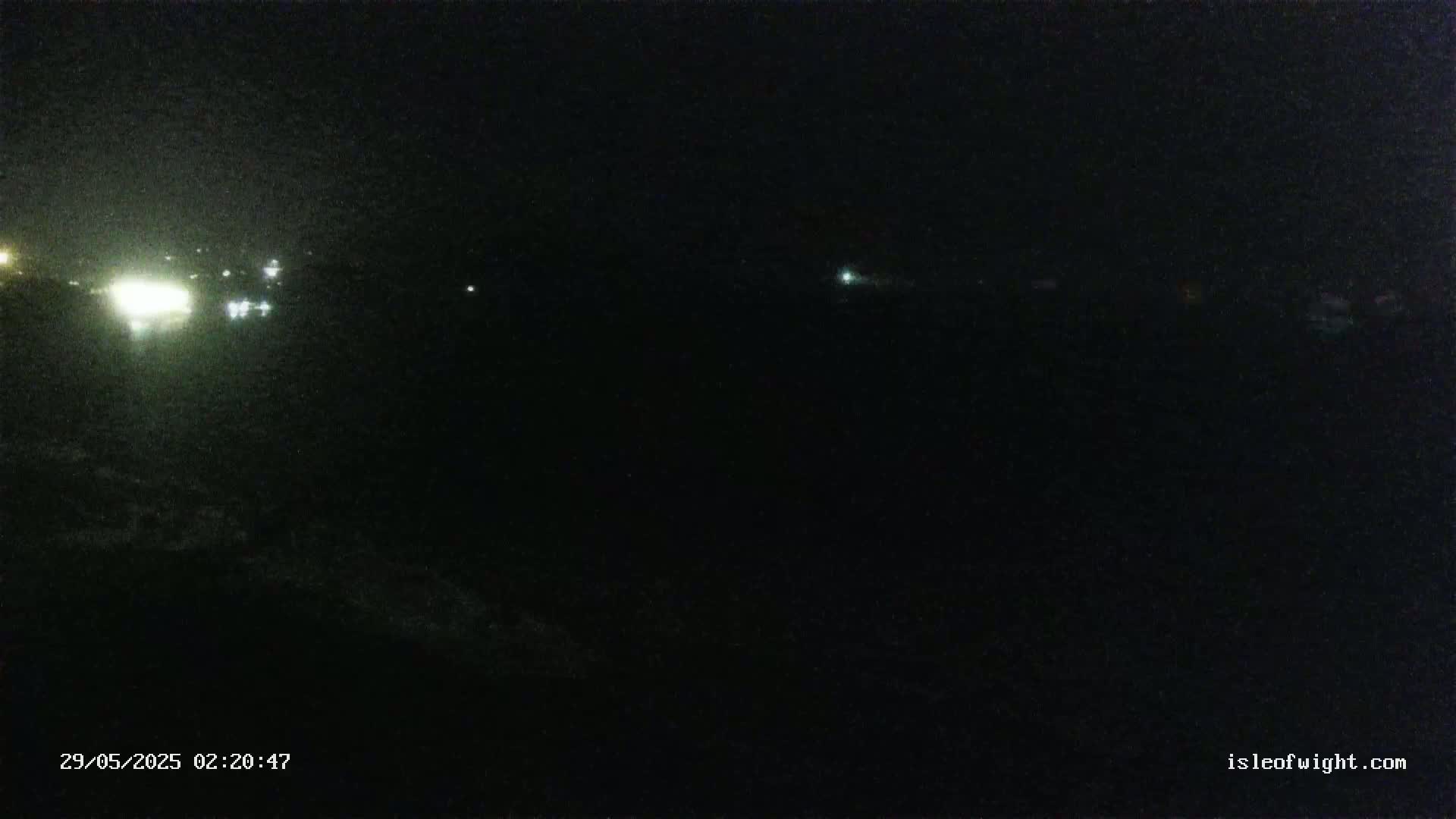A dark, nighttime scene shows a few distant lights in the background.
