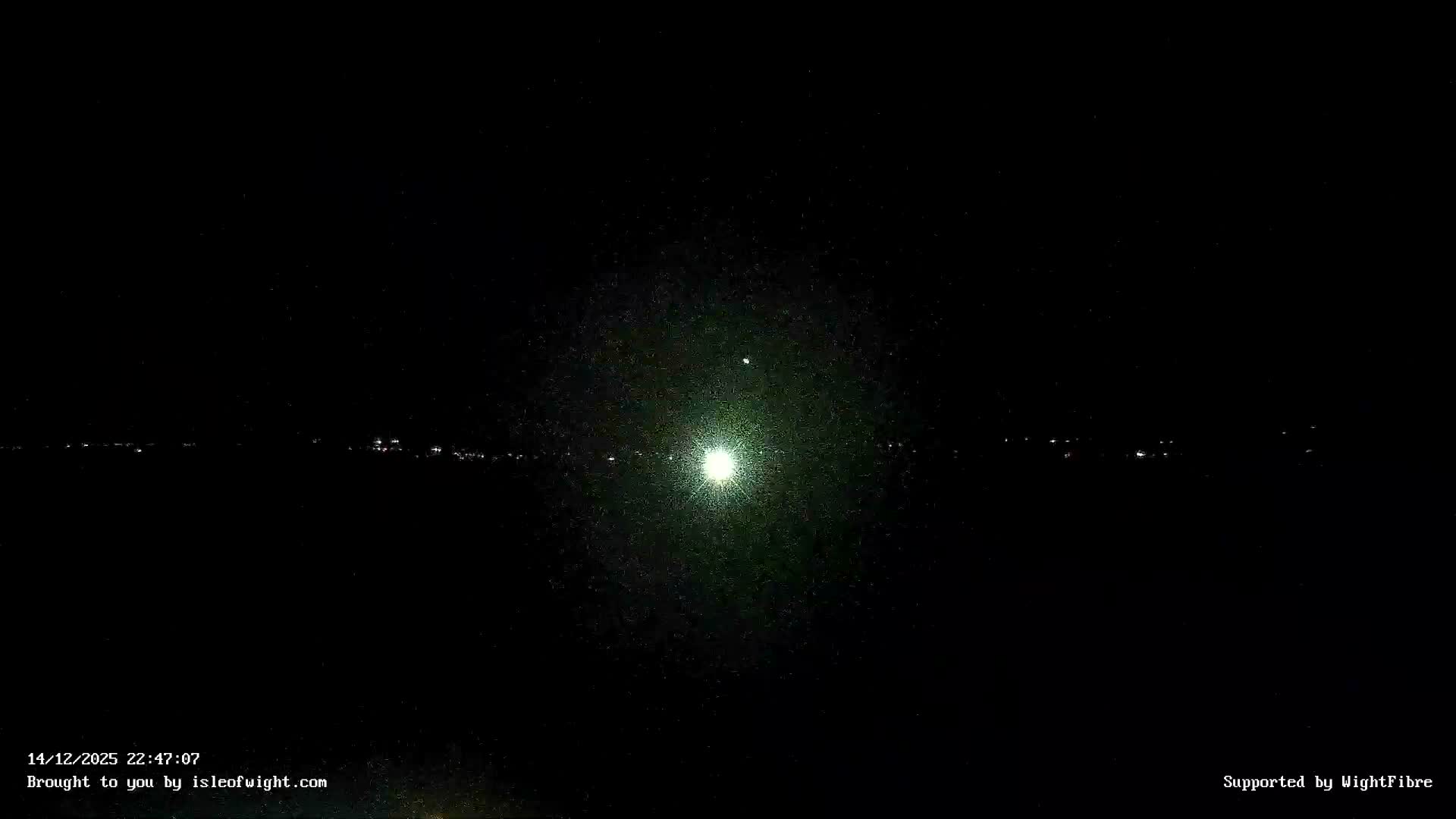 An overcast morning scene reveals choppy grey-green coastal waters, a rocky shore, and dark distant cliffs under a cloudy sky with faint golden light peeking through.