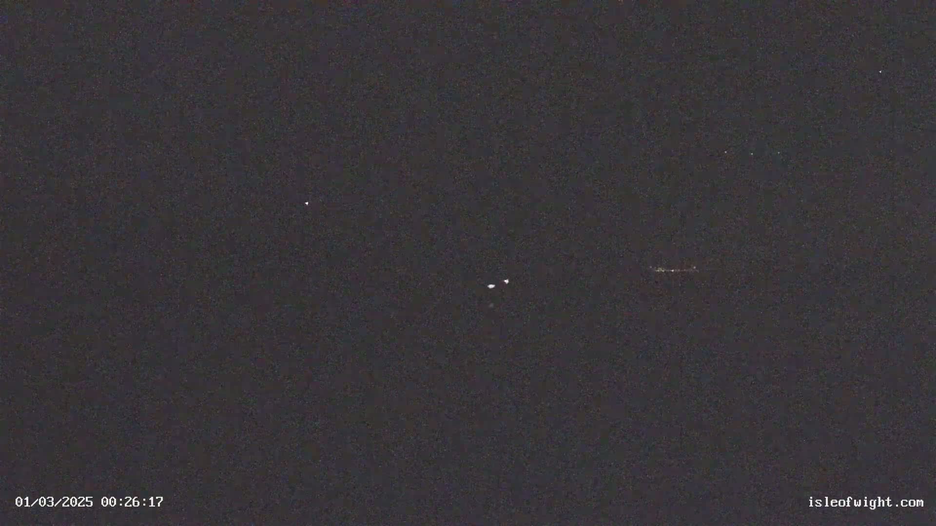 A nighttime, dark sky shows several faint lights.