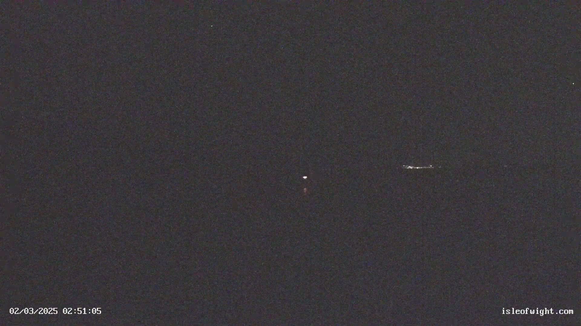 A dark night sky shows a faint, distant light source and a fainter, horizontally-oriented light in the distance.