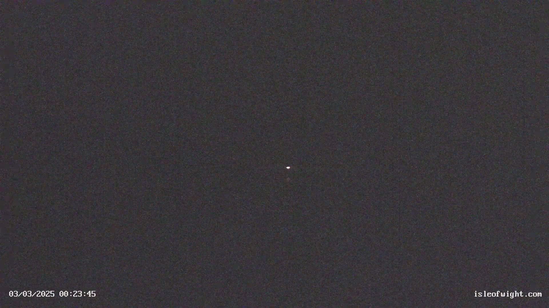 A single, faint point of light is visible in a dark night sky.