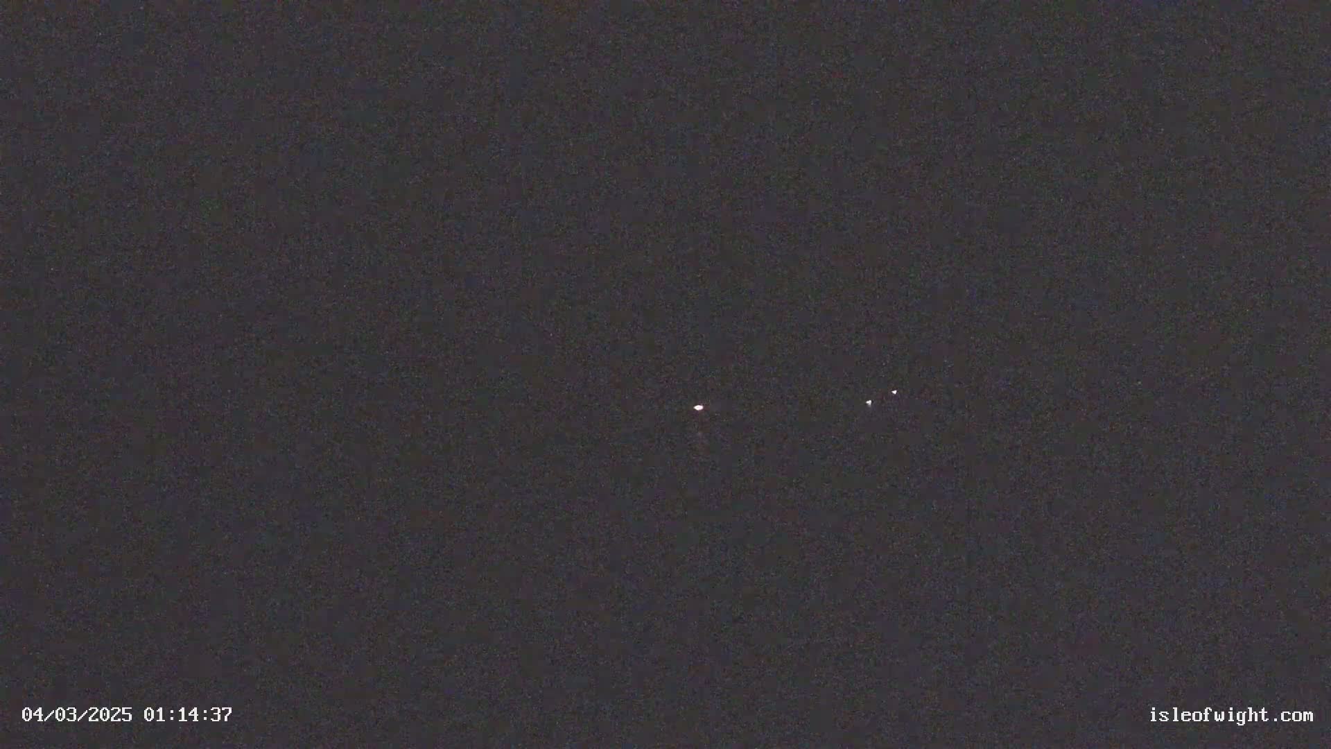 A dark night sky shows three faint lights in the distance.