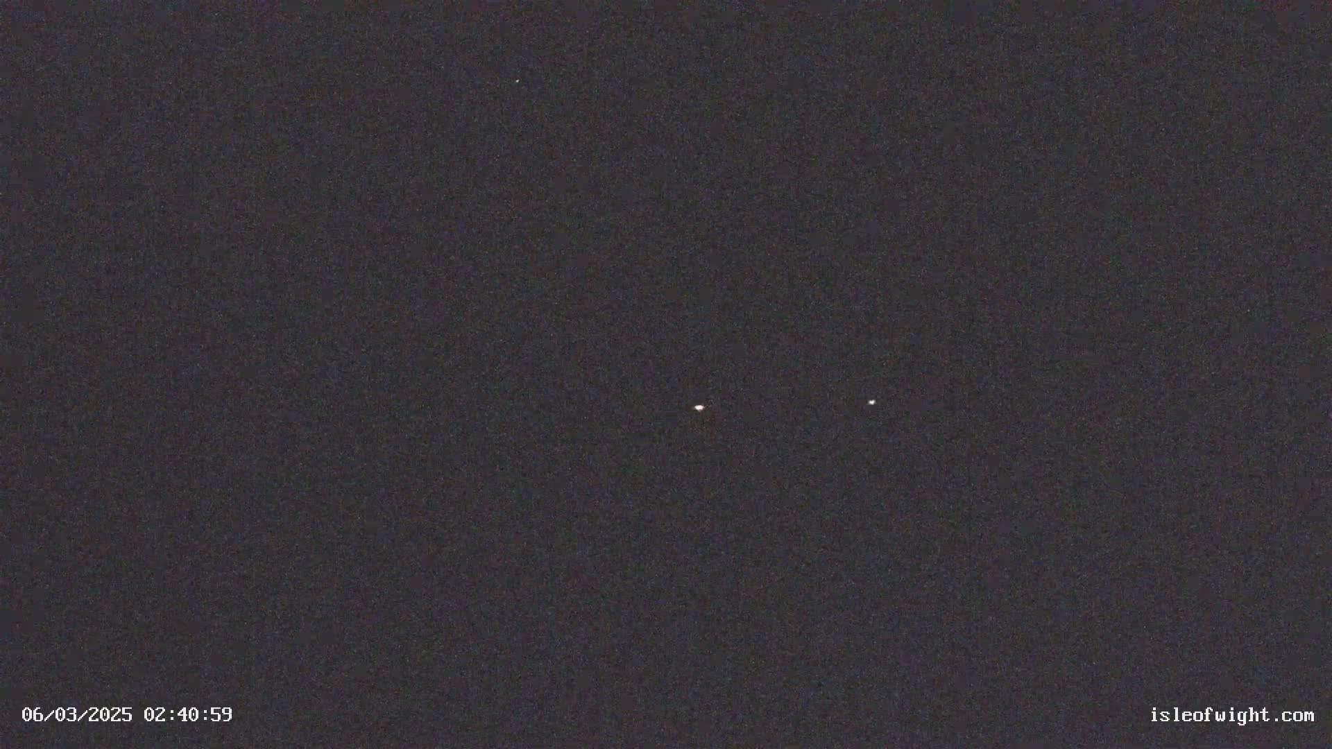 A dark night sky shows three faint, bright points of light.