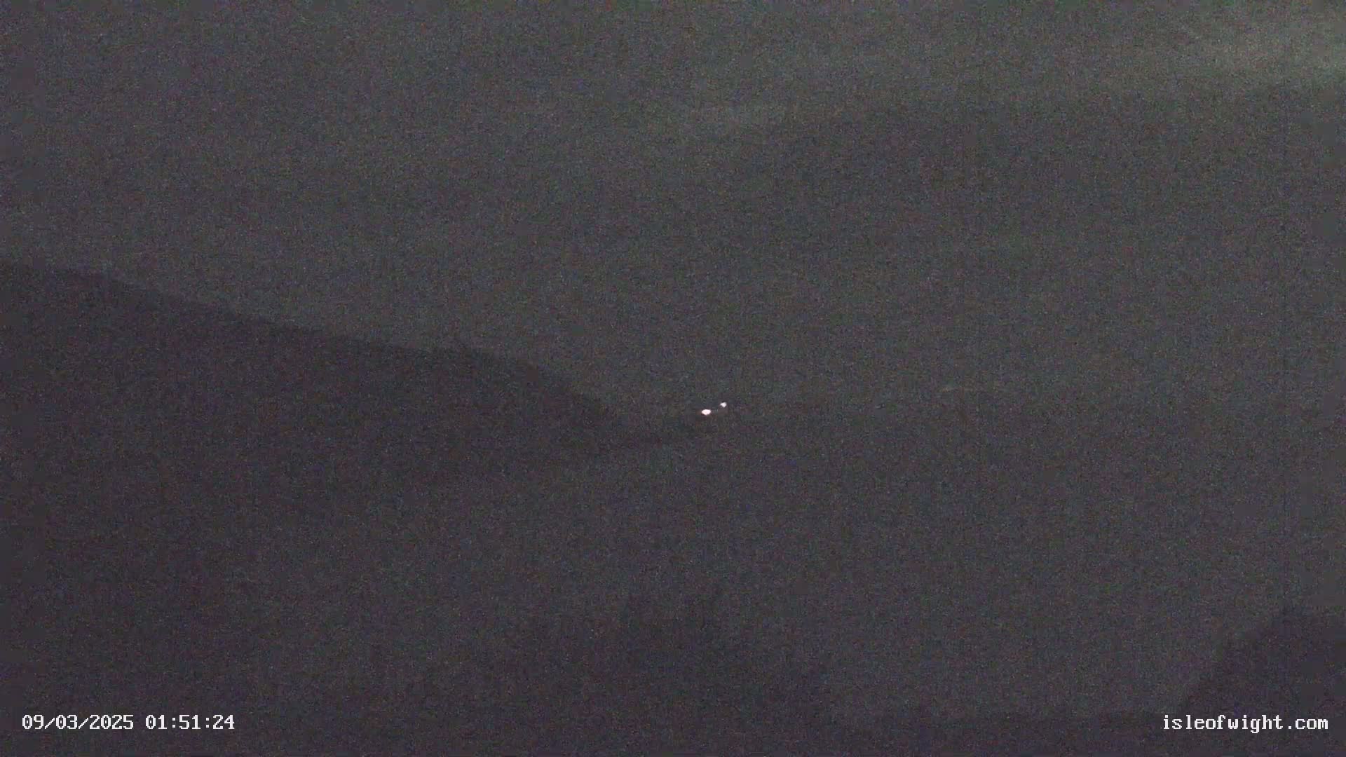 A dark, nighttime image shows two small, faint lights in the distance.