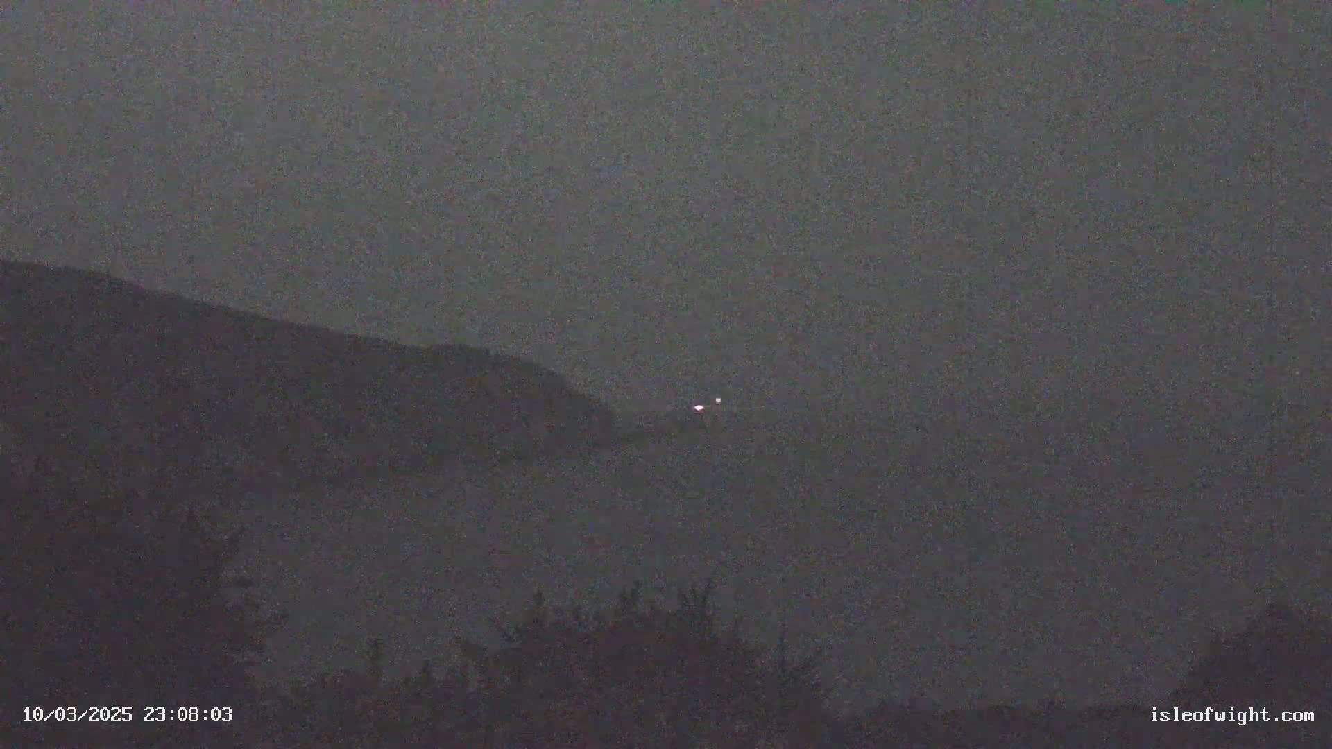 Two faint lights are visible on the horizon over a dark, hazy landscape at night.
