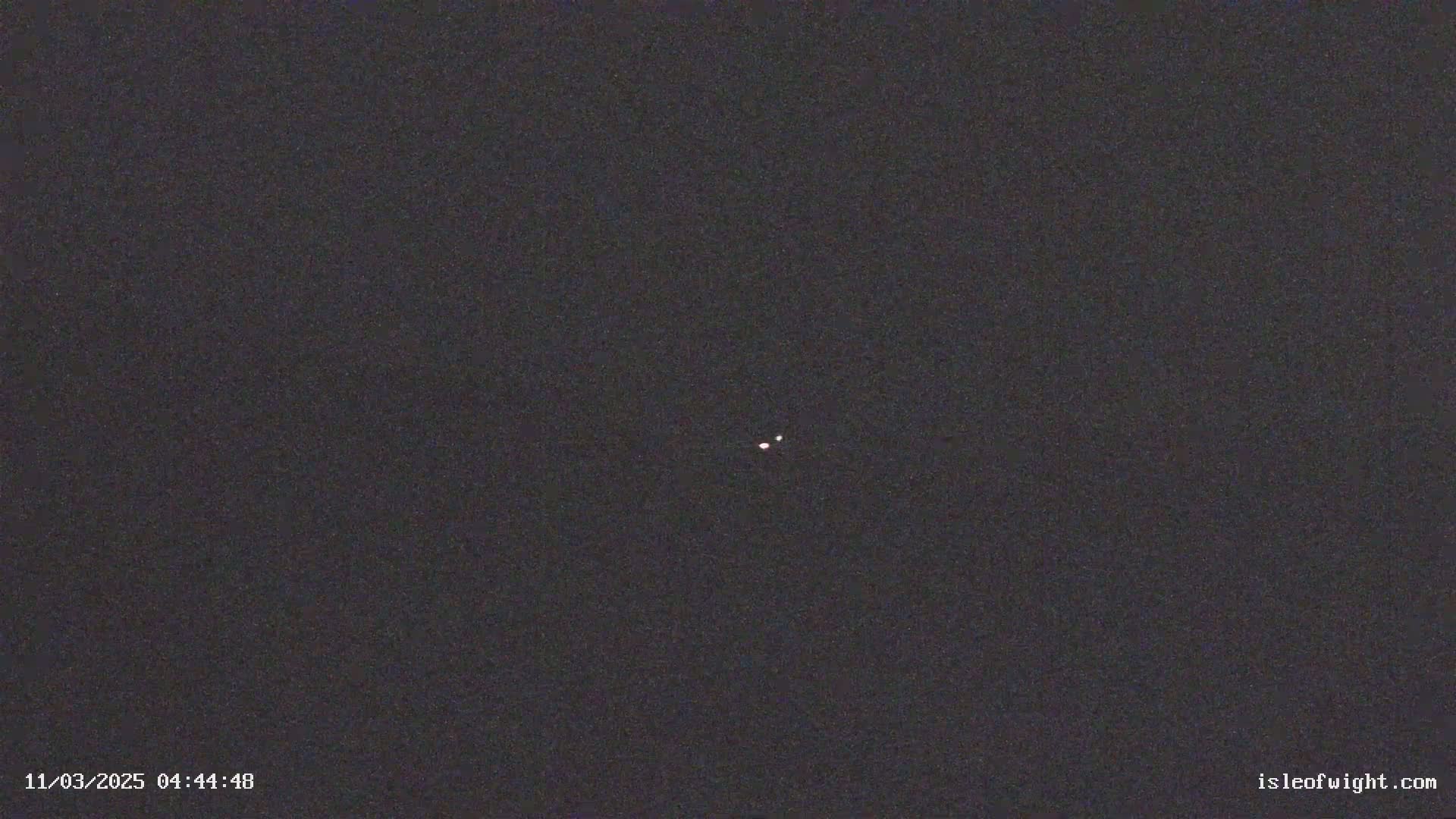 A nighttime image shows two faint celestial bodies in a dark sky.