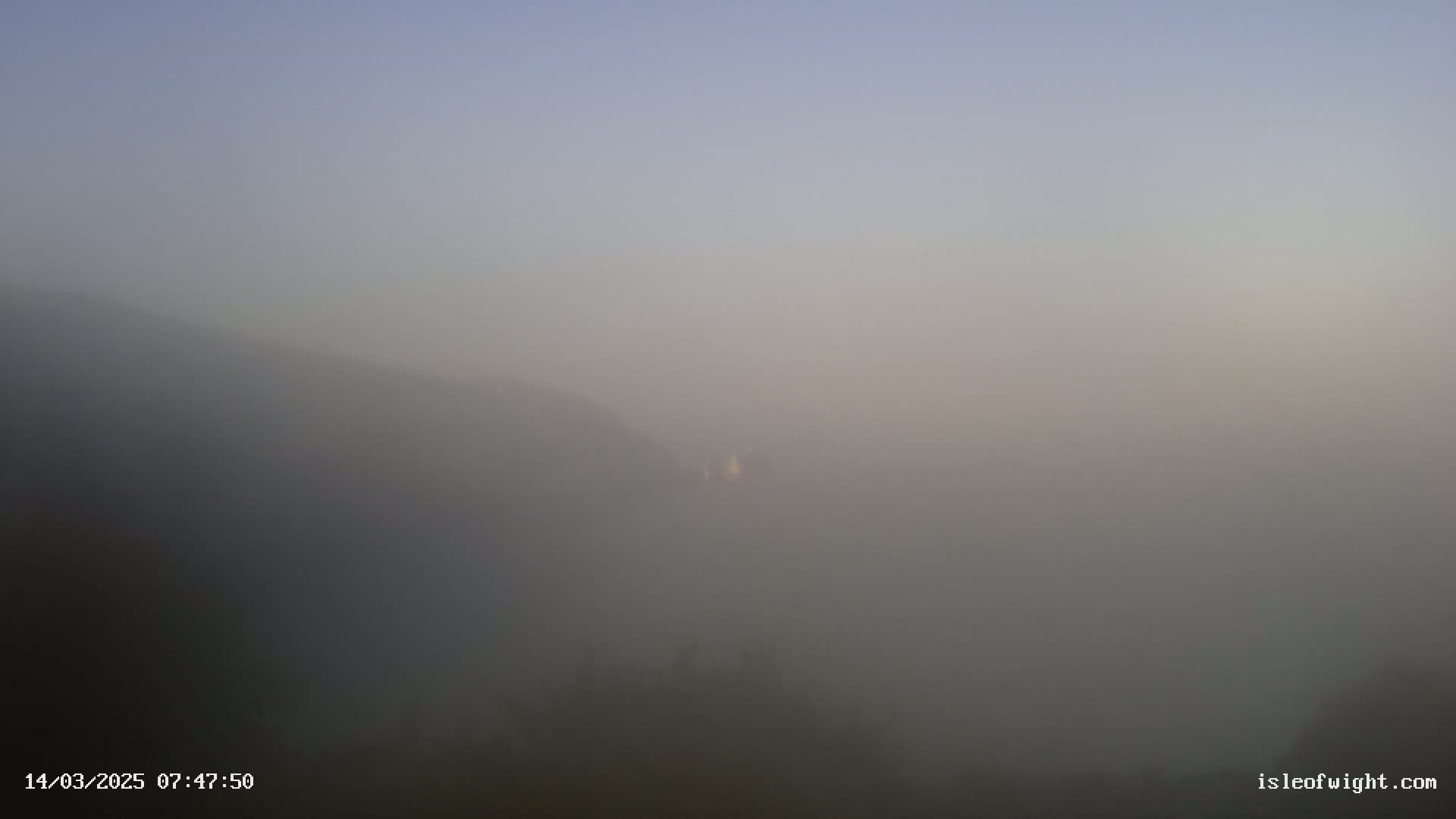 A hazy, foggy landscape reveals indistinct hills and a muted sky.
