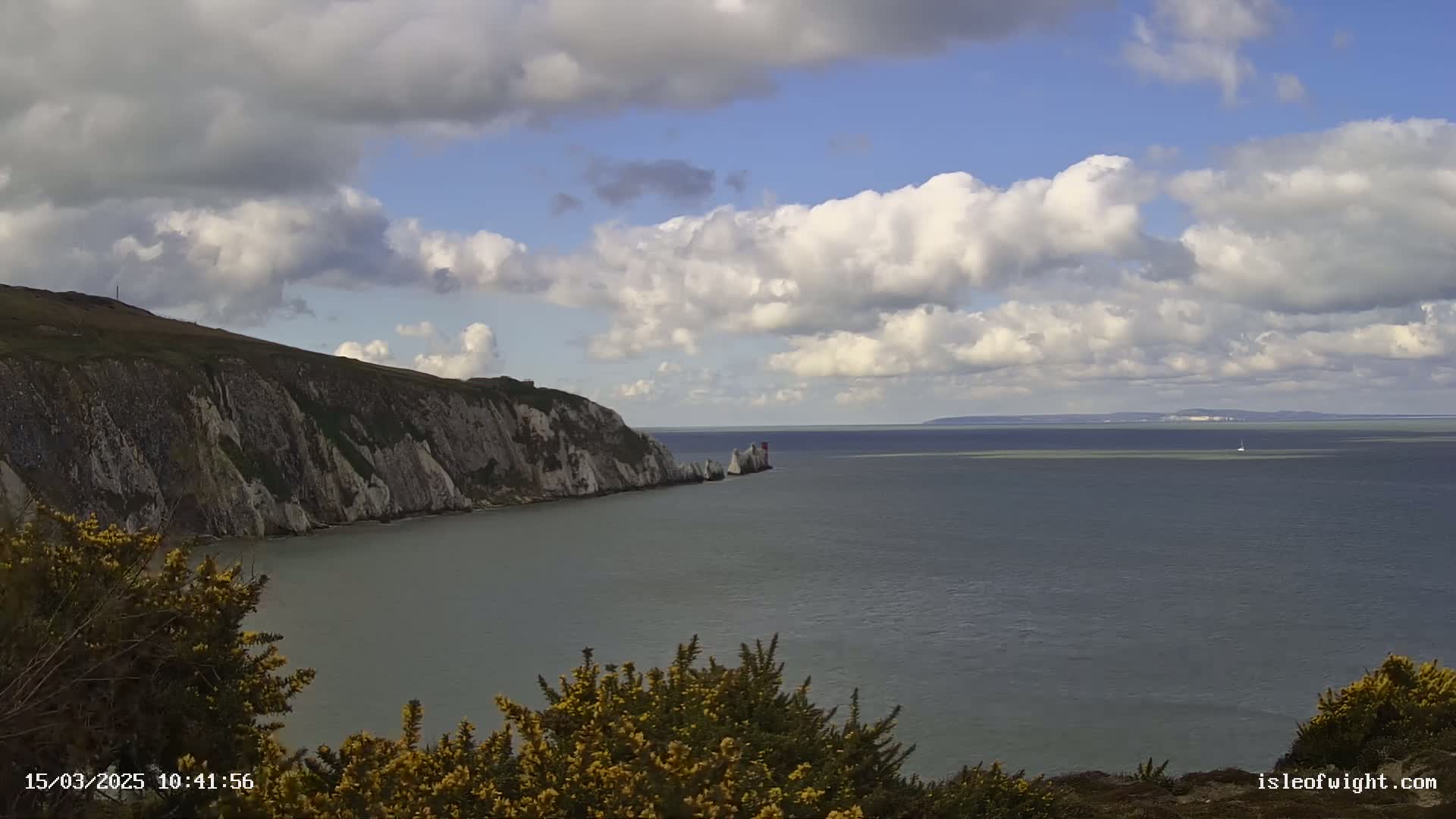 White cliffs meet a calm sea under a partly cloudy sky.