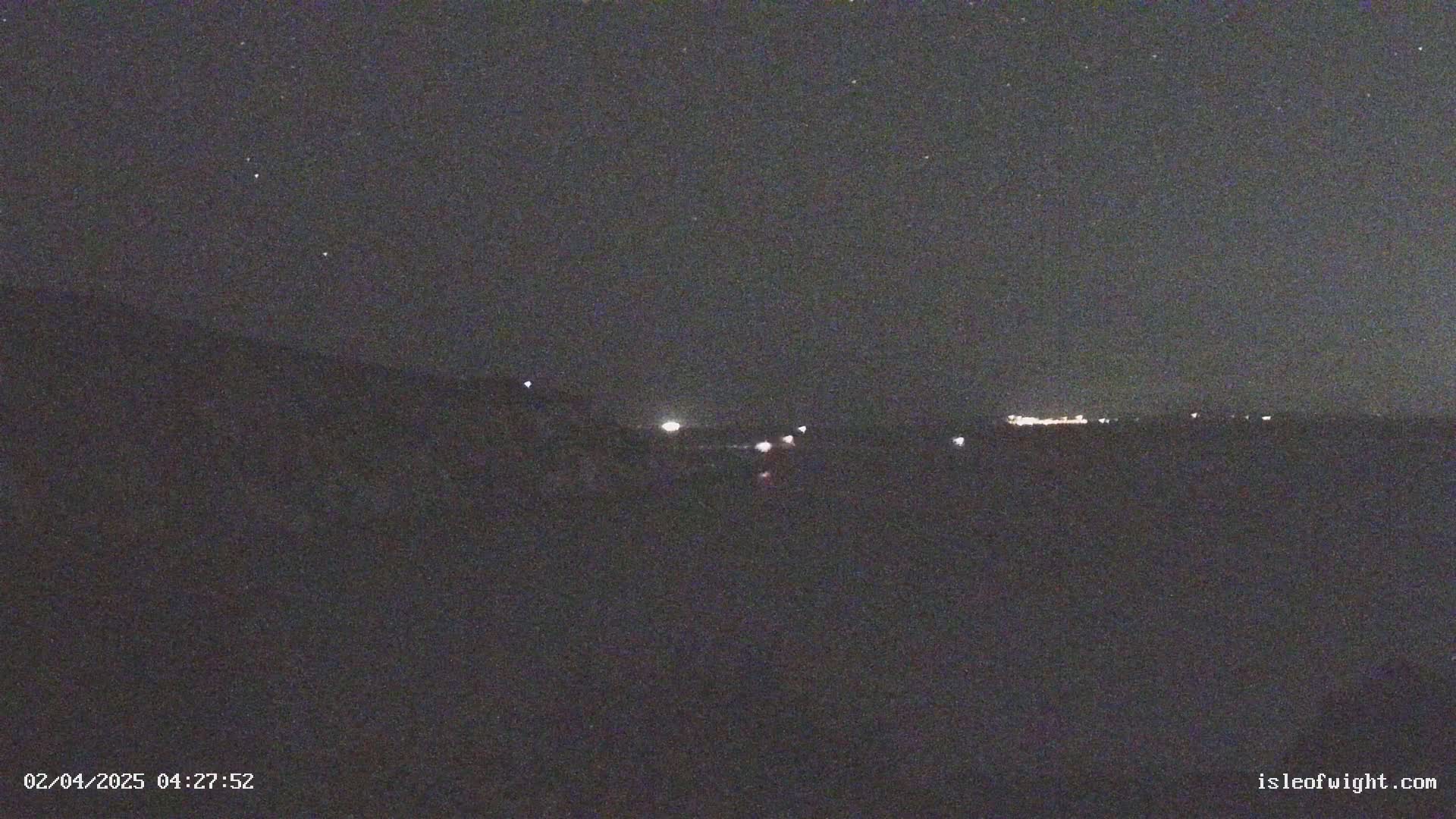 A nighttime, dark landscape is visible with a few distant lights and a starry sky.