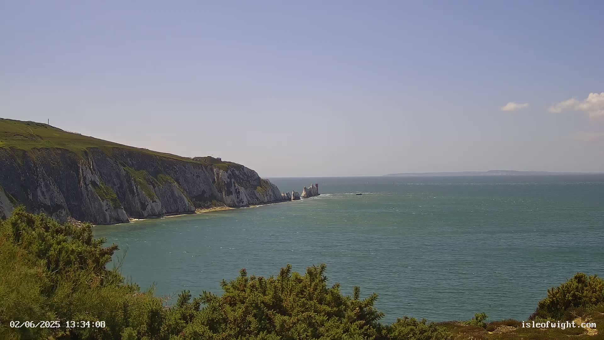 White cliffs meet a teal sea under a mostly clear sky.