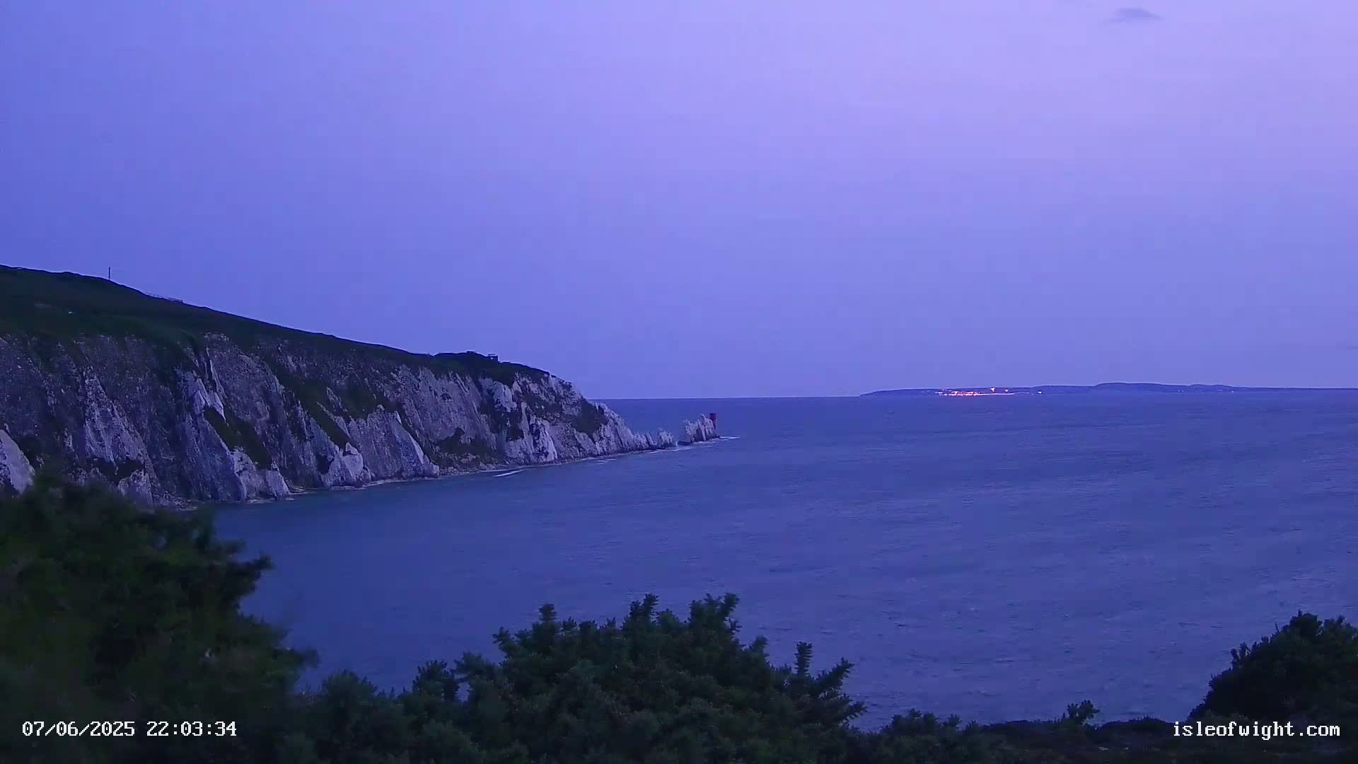 White cliffs meet a calm, dark blue sea under a twilight sky.