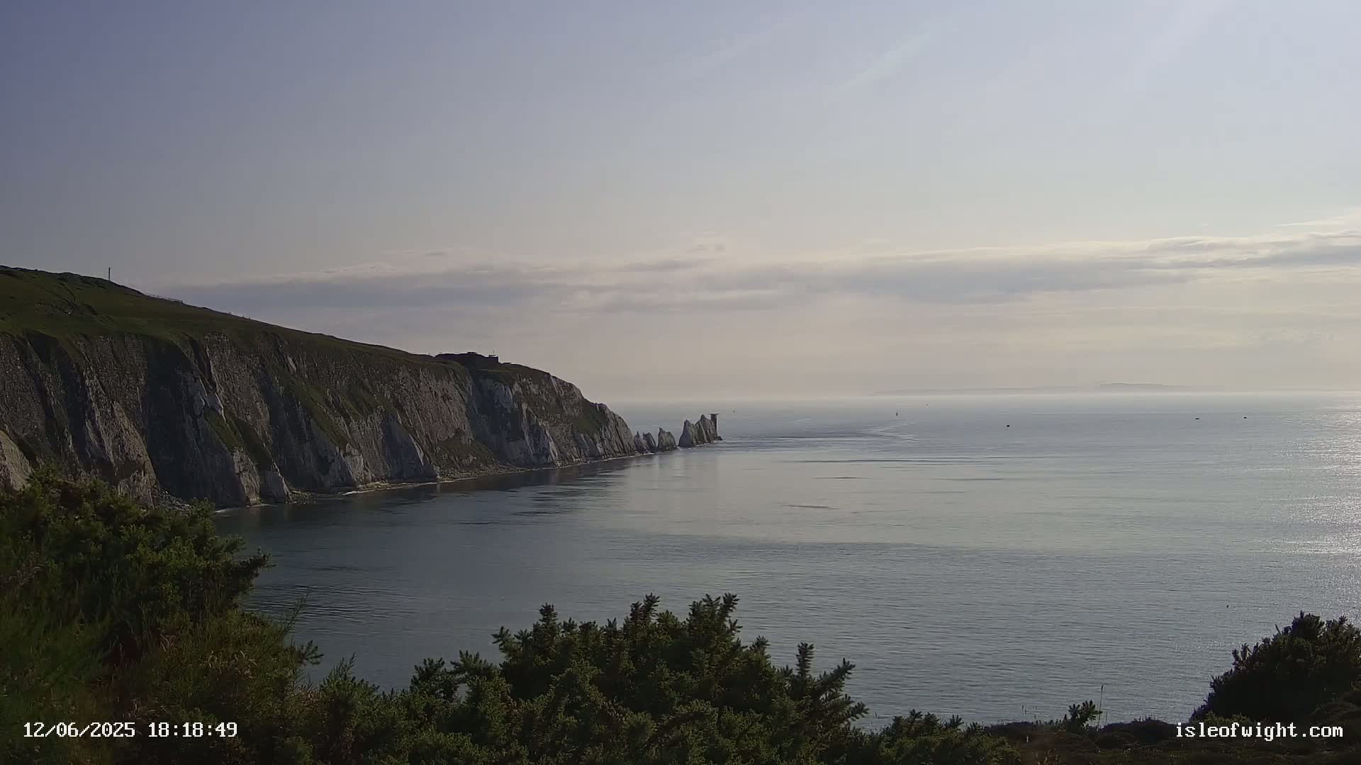 White cliffs meet a calm, hazy sea under a pale sky.