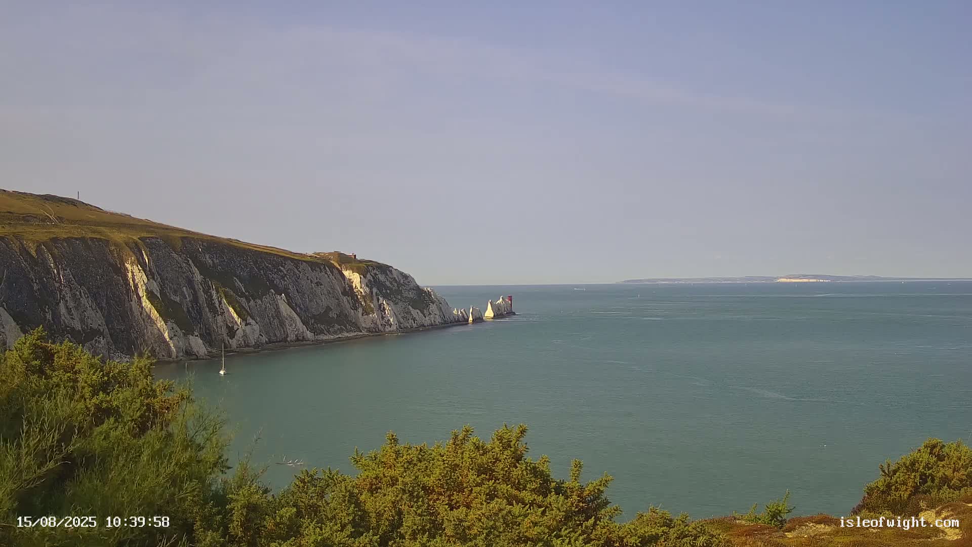White cliffs meet a calm, grey sea under a cloudy sky.