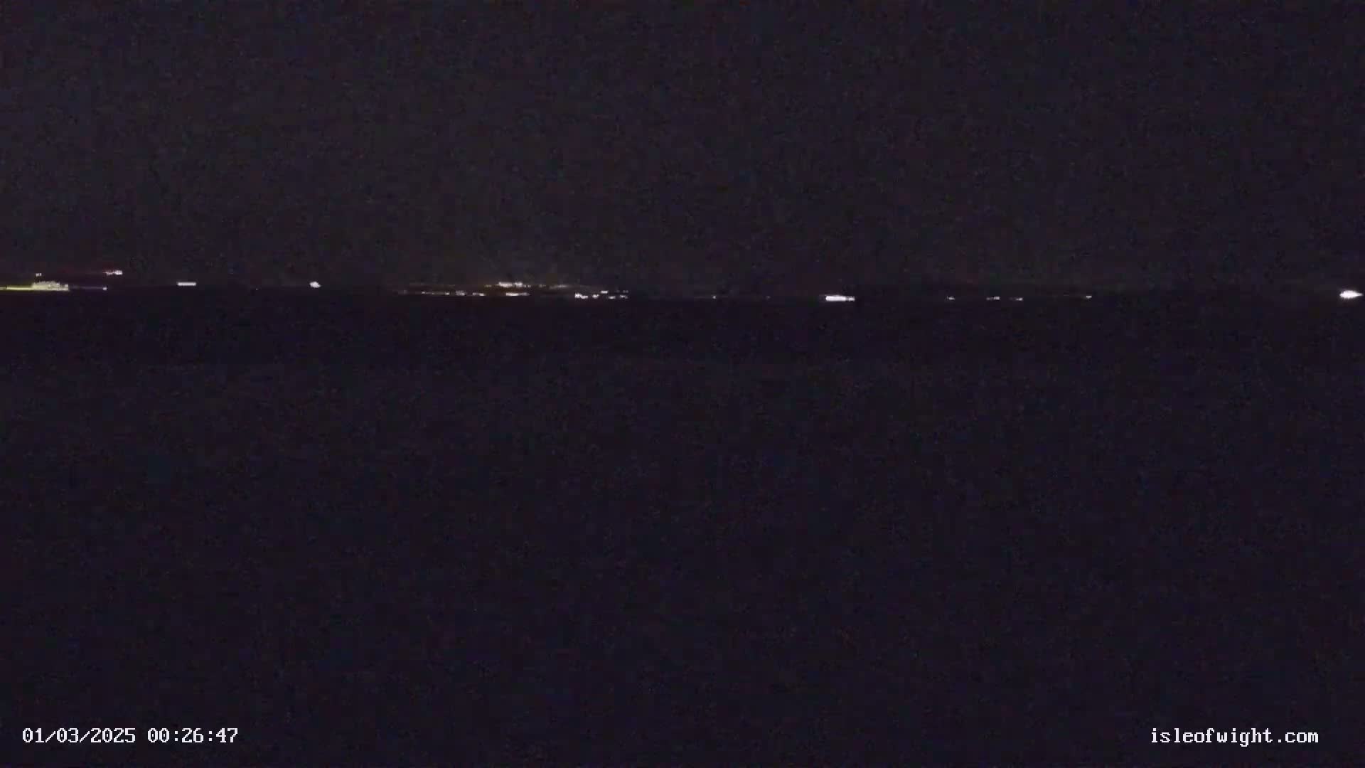 A dark, nighttime view of a distant, faintly lit horizon.