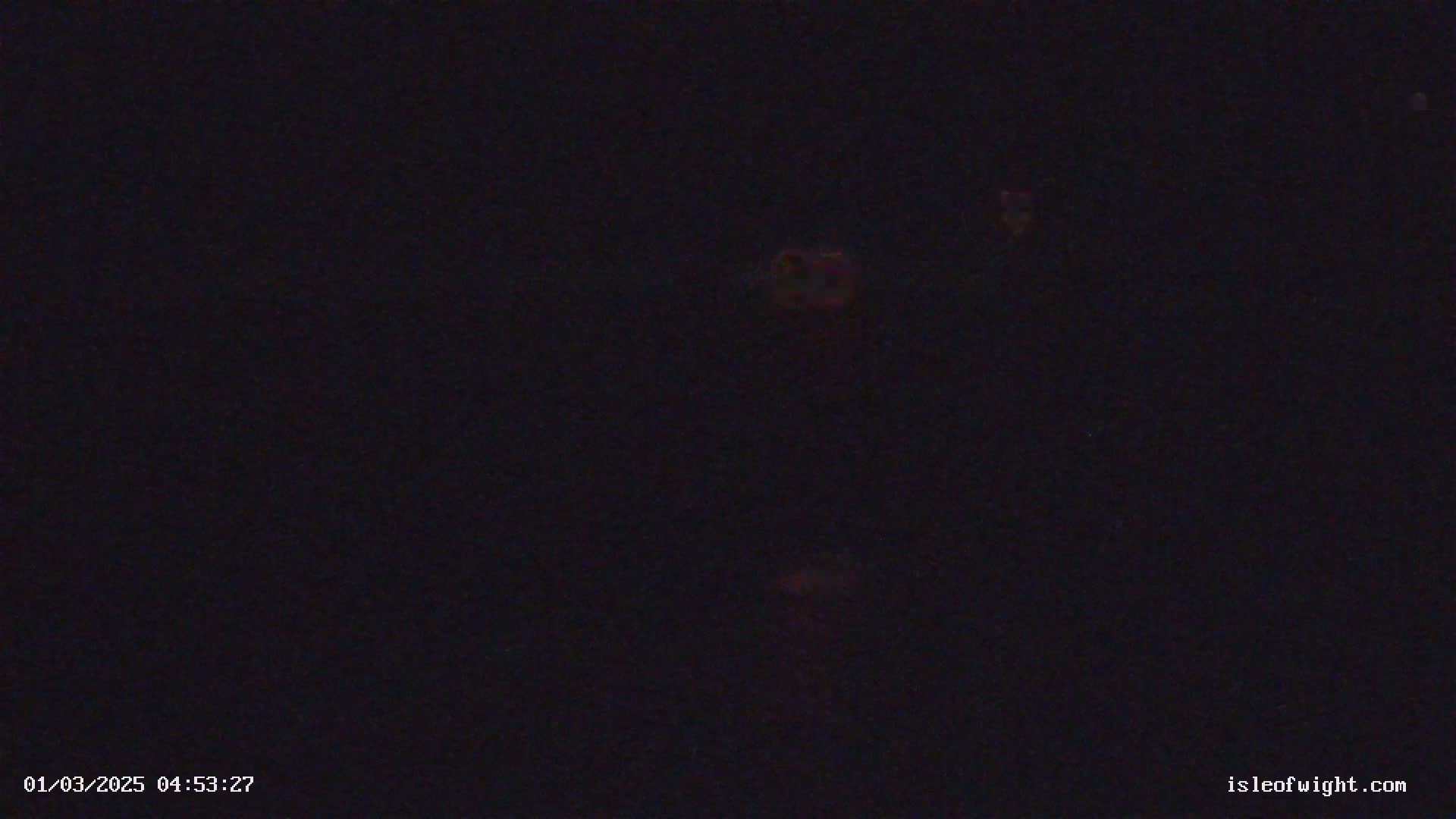 A dark image shows a few faint, blurry lights in the distance at night.