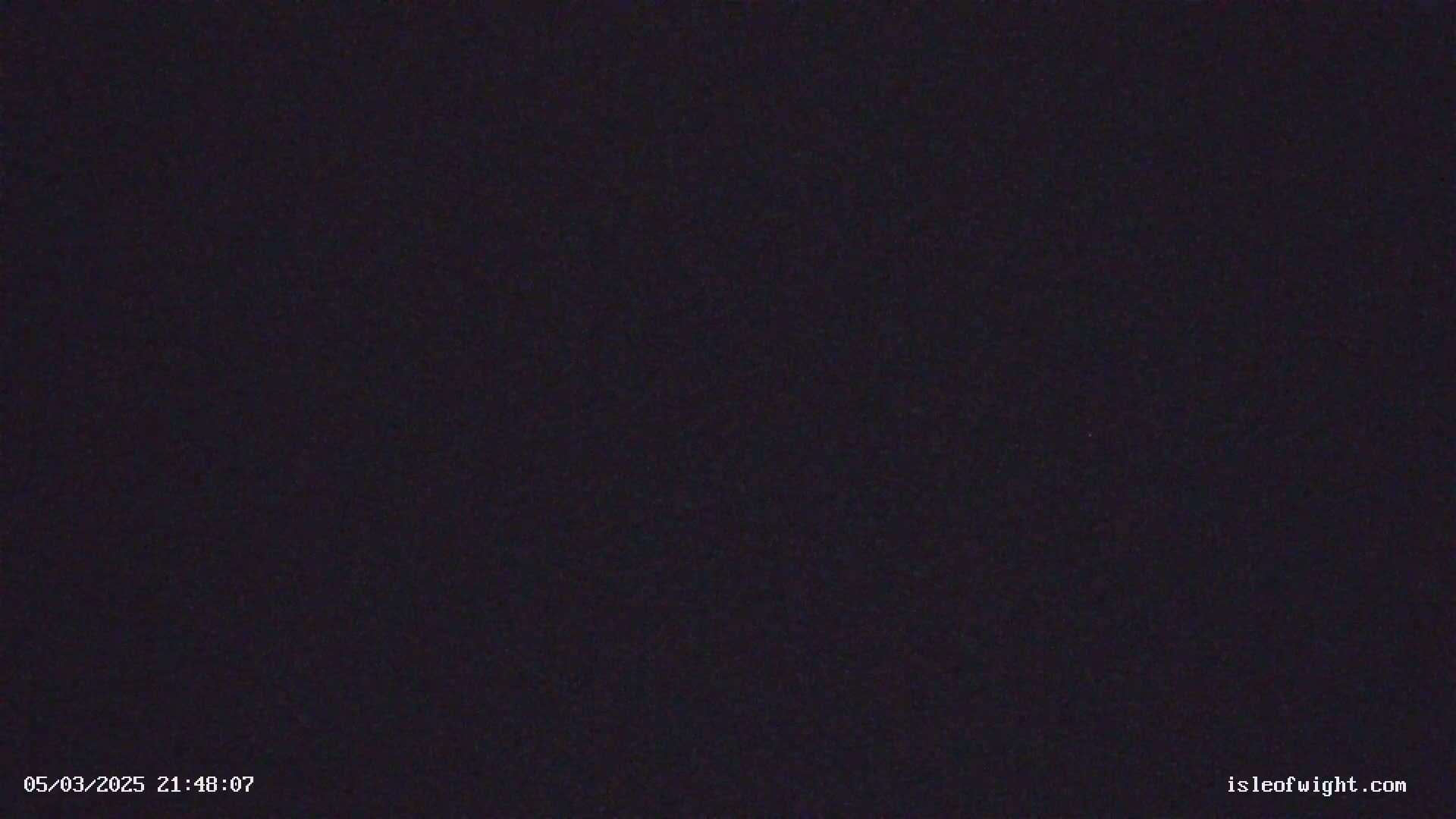 A dark, nighttime image shows a solid black screen with slight grain.