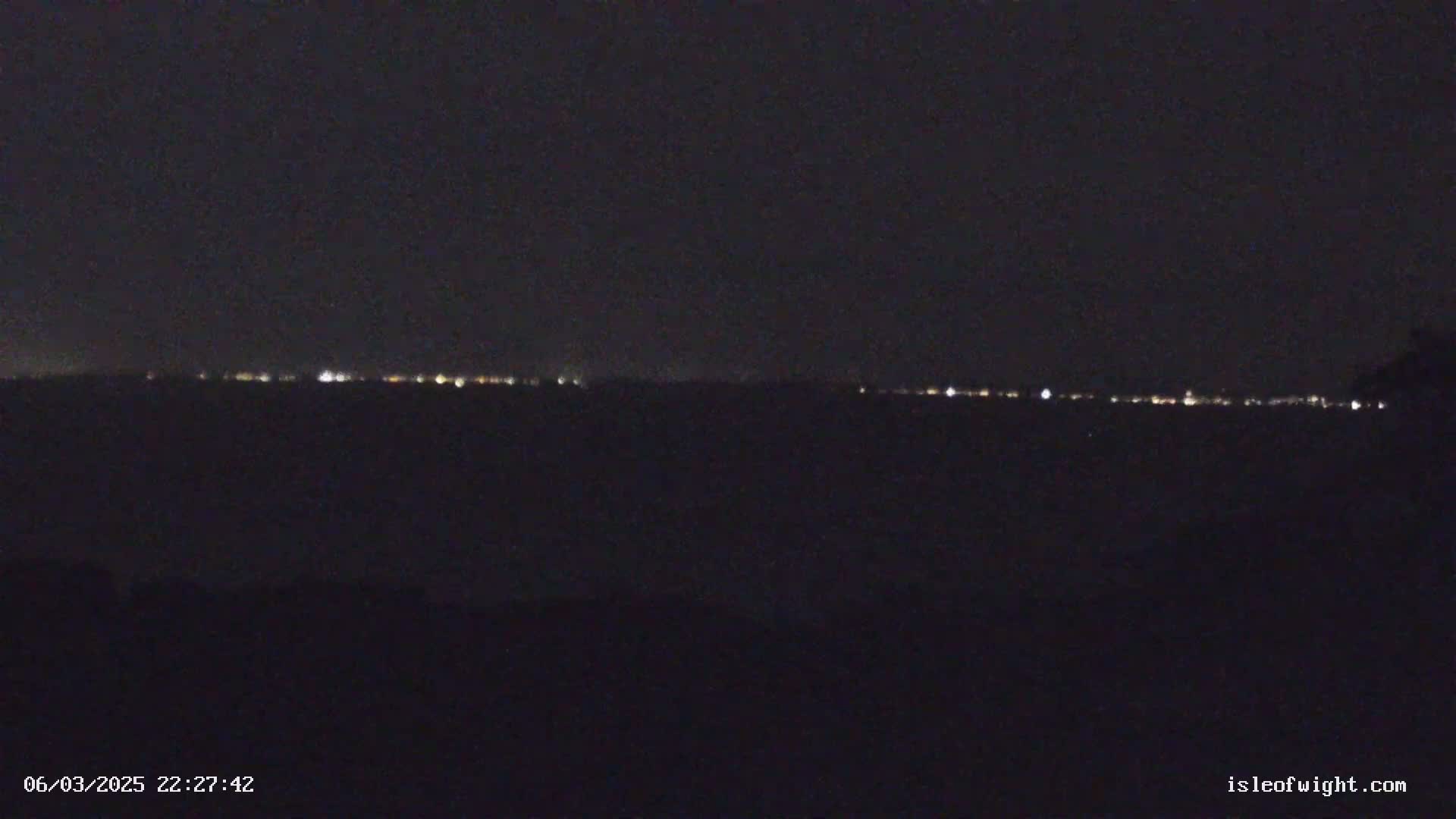A distant line of lights is visible on the horizon at night.