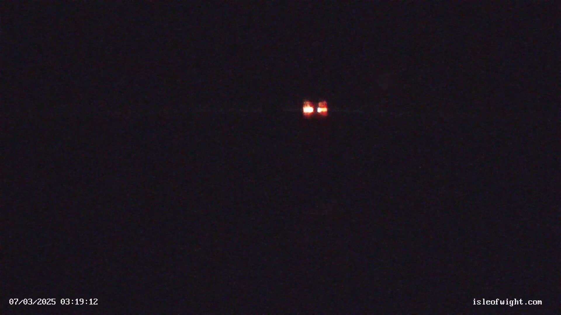 A distant pair of orange lights are visible in the dark night sky.