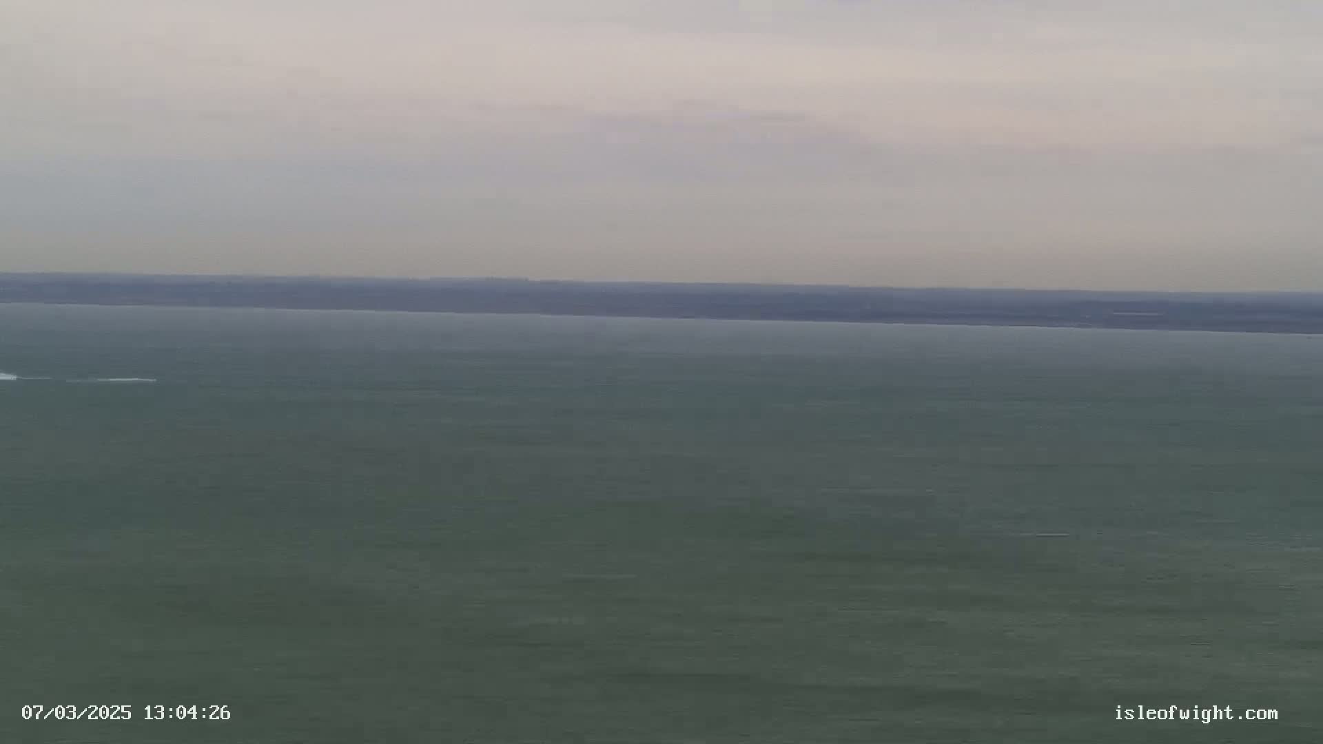 A calm, gray body of water stretches to a dark horizon under an overcast sky.