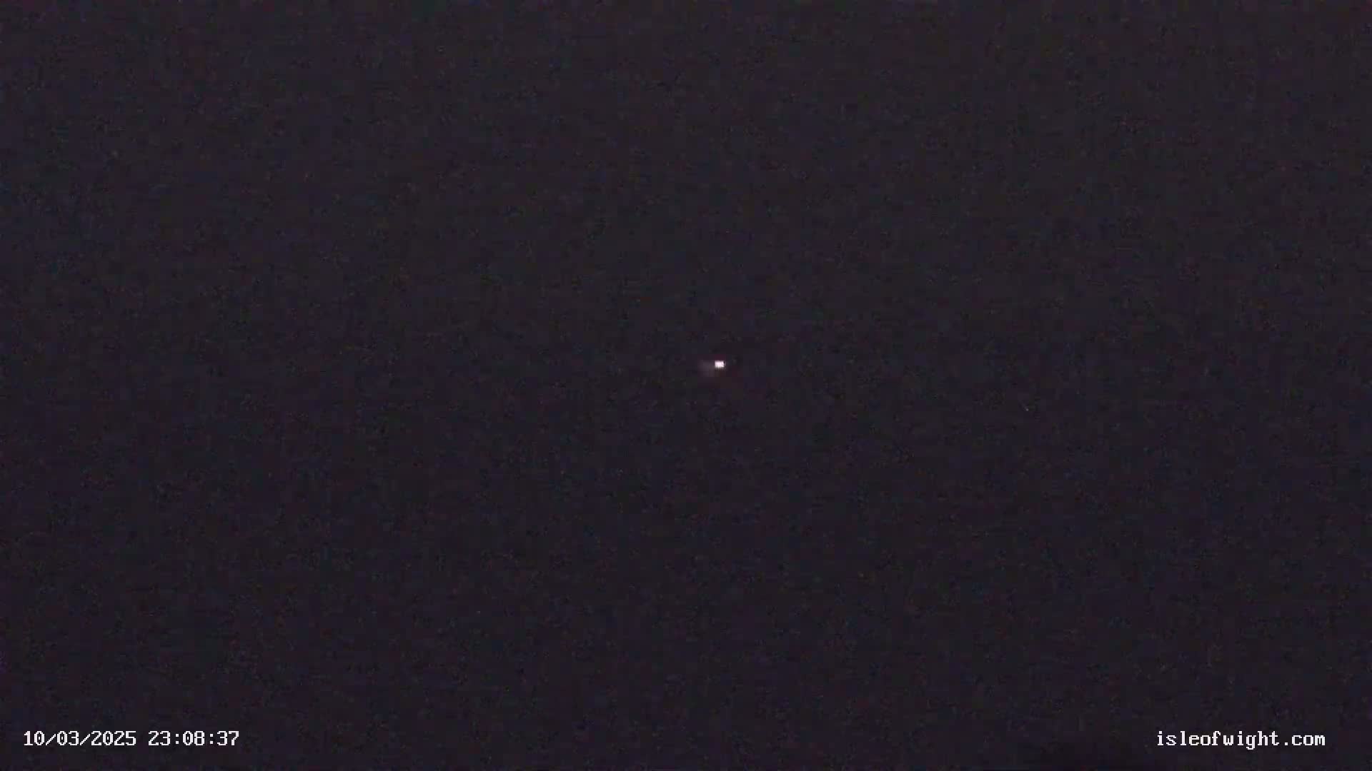 A single, small, faint light is visible in a dark night sky.