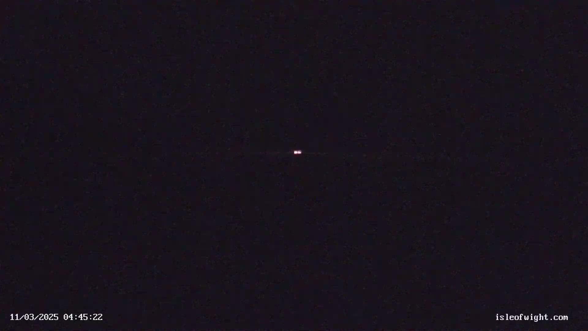 A dark nighttime scene shows two faint, distant lights in the center.