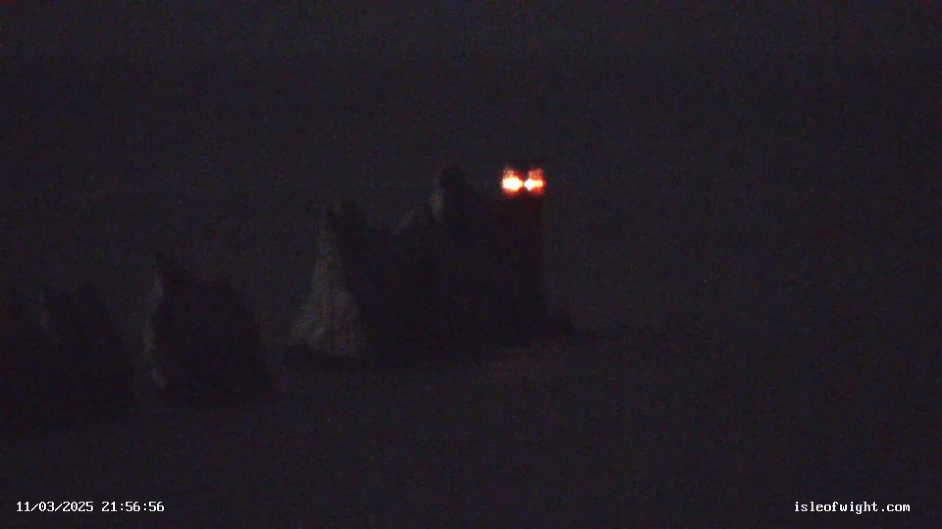 Several dark, indistinct shapes are visible in the low light, with two small, bright orange lights near the center.